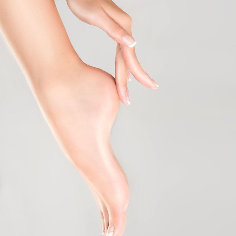 Perfect clean female feet . Beautiful and elegant groomed girl's hand touching  her foot . Spa ,scrub and foot care .